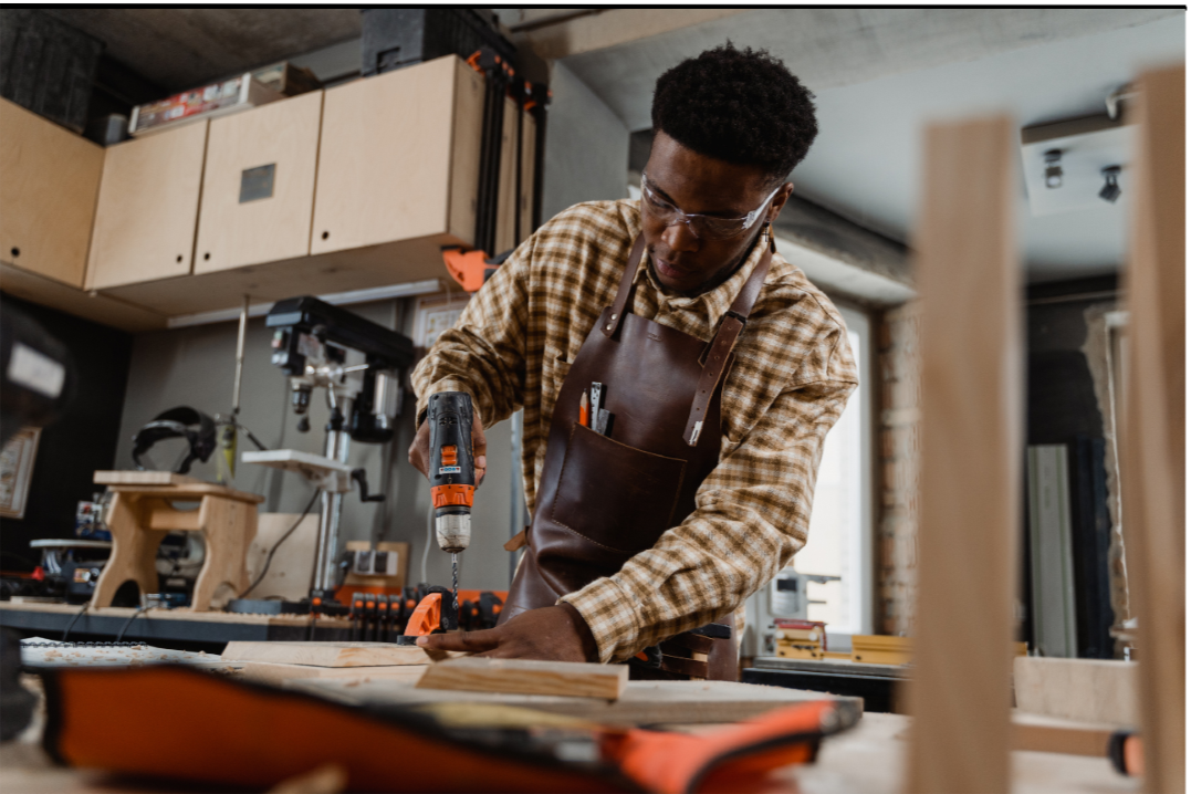 A man using a hand drill on a block of wood