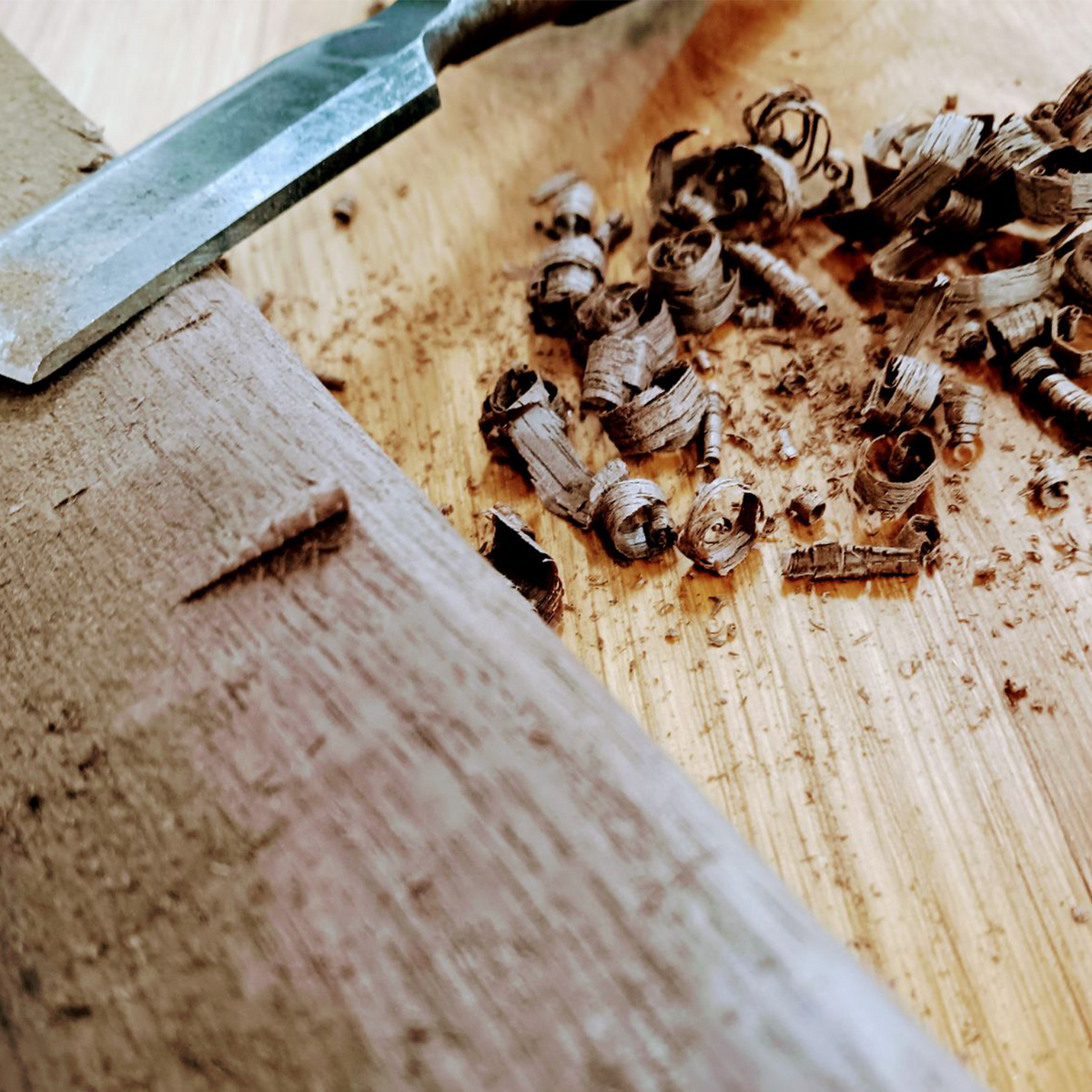 A chisel and shavings on a wood surface