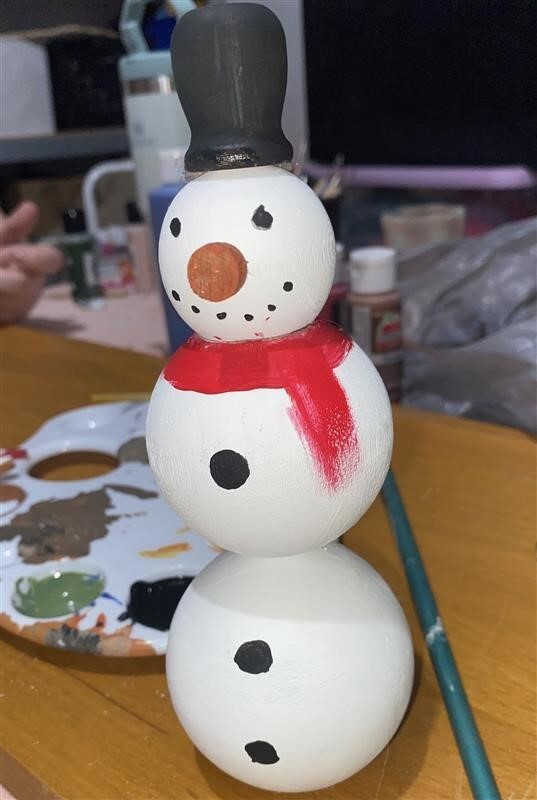 a snow man made of wooden balls glued together and painted